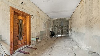 Vstupní hala s dřevěnými dveřmi, betonovou podlahou a vysokým stropem. Potenciál pro rekonstrukci a vlastní úpravy prostoru.