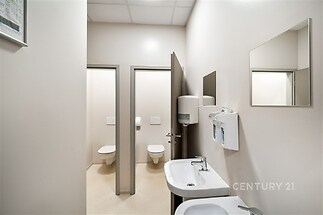 Útulná koupelna s dlažbou, dvě umyvadla, moderní vybavení a oddělené toalety, ideální pro komerční využití.