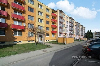Barevný panelový dům s balkony a upraveným vchodem, nacházející se v klidné ulici, vhodný pro rodinné bydlení.