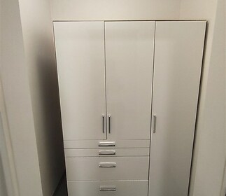 Vestavěná šatna s bílými skříněmi, moderní dlažba, minimalistický design, optimalizuje úložný prostor