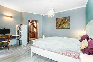 Prostorná ložnice s moderní parketovou podlahou, elegantní světle modré stěny a vestavěné skříně, nabízí pohodlné a stylové bydlení.