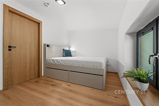 Prostorná ložnice s parketovou podlahou, vestavěnými postelemi a velkým oknem, moderní a světlý design pro komfortní bydlení.