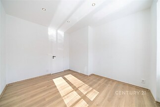 Světlý pokoj s parketovou podlahou a moderním osvětlením, velká okna zajišťují dostatek denního světla, vhodný pro rekonstrukci.