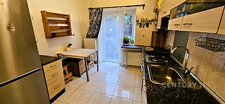 Kompaktní kuchyň s dlažbou, vestavěnými skříněmi a velkým oknem zabezpečujícím dostatek světla, vybavená moderními spotřebiči.