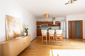 Moderní kuchyň s parketovou podlahou, vestavěnými spotřebiči a světlým dřevěným nábytkem, který doplňuje prostorný interiér.