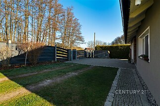 Zahrada s dlážděným chodníkem, velká vstupní brána, travnatá plocha. Klidné prostředí vedle lesa, ideální pro milovníky přírody.