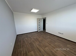 Světlý pokoj s moderními dřevěnými podlahami, neutrálně vymalovanými stěnami a dveřmi s matným sklem, ideální pro flexibilní zařízení.