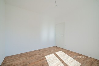 Světlá ložnice s parketovou podlahou, bílými stěnami a moderní povrchovou úpravou, ideální pro osobní úpravy a dekorace.