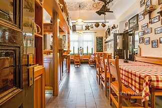 Restaurace s dřevěným nábytkem, dlažbou na podlaze a dekorativními prvky na stěnách, vytvářející rustikální atmosféru.