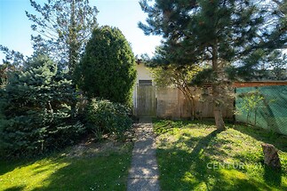 Zahrada s udržovaným trávníkem, obklopená vzrostlými stromy, dodává soukromí a klidnou atmosféru ideální pro relaxaci.