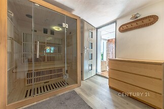 Domácí sauna s prosklenými dveřmi, dřevěné obložení a světlé parketové podlahy, nabízí moderní relaxační prostor s přístupem na terasu.