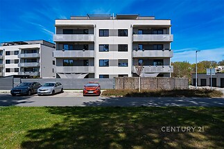 Moderní bytový dům s balkony a parkovištěm, v klidné lokalitě. Elegantní fasáda kombinuje moderní design s praktickým uspořádáním.