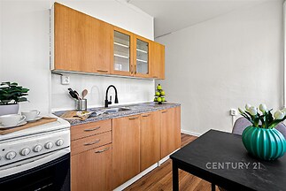 Moderní kuchyň s parketovou podlahou a dřevěnými skříňkami, vybavená sporákem, velkým dřezem a elegantní pracovní deskou.