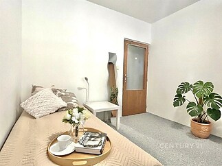 Světlý pokoj s moderním nábytkem, parketová podlaha, velké zrcadlo, minimalistický styl, útulný prostor ideální pro relaxaci.