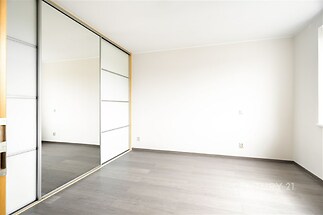 Prázdný pokoj s vestavěnými skříněmi, moderní parketová podlaha a světlá výmalba, vhodný pro osobní úpravy nebo zařízení dle přání.