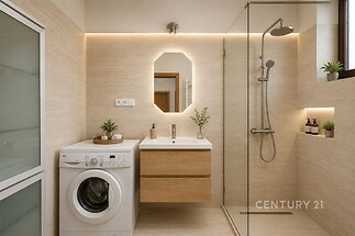 Moderní koupelna s dlažbou, sprchovým koutem a vestavěnými skříněmi. Minimalistický design je doplněn světlým osvětlením a pračkou.