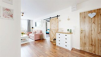 Vstupní hala s parketovou podlahou a dřevěnými dveřmi, světlá dekorace, moderní styl, přechází do obývacího pokoje s velkými okny.