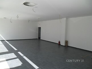 Světlý obývací prostor s dlažbou, velkými okny a moderními stropními rozvody, ideální pro otevřený design interiéru