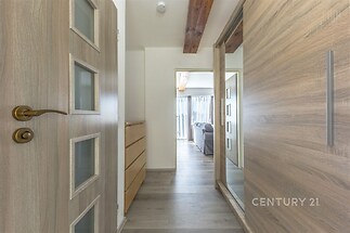 Úzká chodba s dřevěnými dveřmi a vestavěnými skříněmi, světlý interiér, parketová podlaha, moderní design, velká okna v obývacím pokoji.