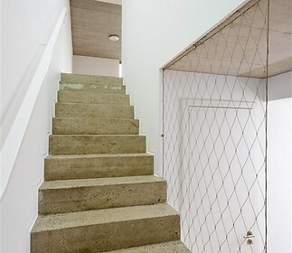 Schodiště s moderním betonovým povrchem a minimalistickým designem, nabízí světlý a prostorný interiér, ideální pro moderní domov.