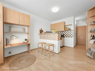 Kompaktní kuchyň s parketovou podlahou, dřevěnými skříňkami a moderními světly, vedle vestavěného pracovního prostoru s policemi.