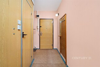 Chodba s dlažbou, dřevěnými dveřmi a vestavěným věšákem nabízí funkční prostor. Světlé stěny doplňují moderní interiér.