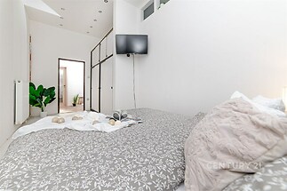 Světlá ložnice s moderním designem, vestavěné skříně, parketová podlaha a prostorný interiér s minimalistickými dekoracemi.