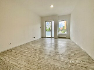 Světlý obývací pokoj s moderní parketovou podlahou, velká okna zajišťují dostatek přirozeného světla, prostor je ve výborném stavu.