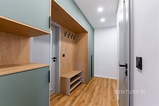 Chodba s dřevěnou podlahou, vestavěné skříně v moderním designu, stropní osvětlení zajišťující světlost prostoru.