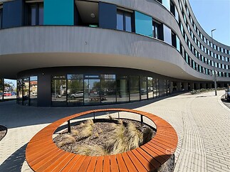 Moderní komerční budova s obloukovým designem, velká okna, dlažba na chodníku, moderní architektura