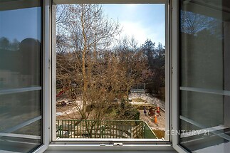 Výhled z okna na udržovanou zahradu s dětským hřištěm, velká okna, klidná lokalita, ideální pro rodiny s dětmi.