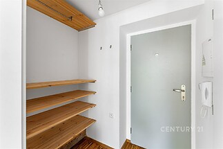 Vstupní hala s dřevěnými policemi, parketovou podlahou a moderními dveřmi nabízí praktický úložný prostor a stylový design.