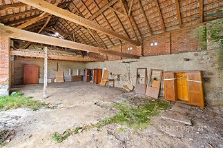 Prostorná stodola s kamennými stěnami, dřevěnými trámy a velkým potenciálem pro rekonstrukci, vhodná pro kreativní využití nebo přestavbu.