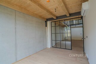 Průmyslový interiér s dřevěnými stropy, betonovými stěnami a skleněnými integrovanými dveřmi. Moderní design s kvalitními materiály.