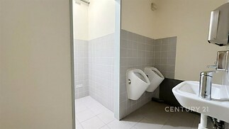 Veřejné sociální zařízení se světlými dlaždicemi, keramickými pisoáry a moderní umyvadlem, vhodné pro komerční prostory.