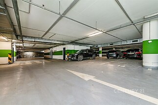 Podzemní garáž s hladkým betonovým povrchem a moderní osvětlení nabízí bezpečné parkování.