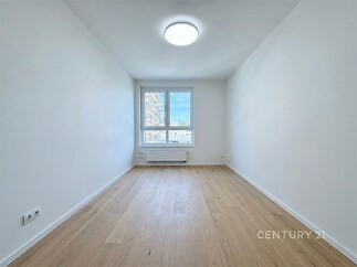 Světlý pokoj s parketovou podlahou, velkými okny a moderním osvětlením. Vhodný pro rekonstrukci nebo jako investiční příležitost.