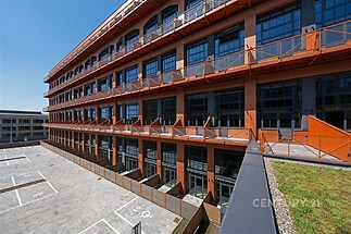 Zrekonstruovaná průmyslová budova s moderními prvky, velká okna a terasa, vhodná pro komerční využití.