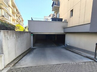 Podzemní parkoviště s betonovou podlahou a moderním osvětlením, vhodné pro rezidenční domy, v těsné blízkosti městské infrastruktury