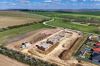 Staveniště rodinných domů v přírodě, moderní cihlová konstrukce, klidné okolí s výhledem na pole a hory, vhodné pro novou zástavbu.