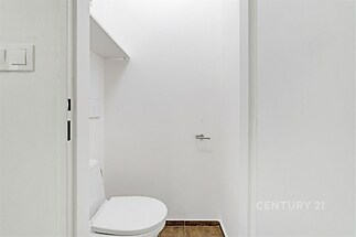 Jednoduchá koupelna, dlažba na podlaze, bílé stěny, moderní minimalistický design, prostor je perfektně osvětlený.