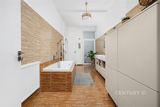 Prostorná koupelna s dlažbou v dřevěném designu, moderní vanou a vestavěnými skříněmi, světlý prostor s elegantním osvětlením.