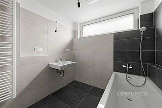 Moderní koupelna s černobílou dlažbou, velkým oknem a stylovým vybavením včetně vany a sprchy, světlý interiér.