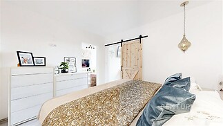 Světlá ložnice s dřevěnými posuvnými dveřmi, moderní dekorací a světlým nábytkem, která nabízí klidnou atmosféru a útulný styl.