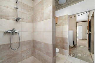 Koupelna s dlažbou, sprchovým koutem a moderním designem nabízí neutrální tóny a kvalitní provedení, vhodná k okamžitému využití.