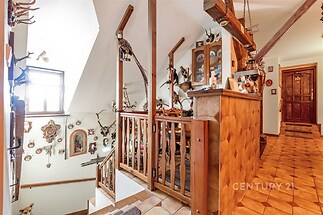 Podkrovní prostor s dřevěnými trámy a dlažbou, zdobený loveckými trofejemi, nabízí rustikální styl a autentickou atmosféru.