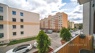 Výhled z balkónu na sídliště s panelovými domy, moderní rekonstrukce, prostorný balkon, klidná lokalita, parkování na ulici.