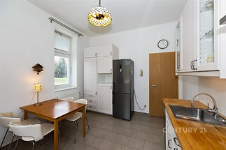 Kuchyň s dlažbou, moderní vybavení, světlá plocha s velkou lednicí a dřevěnou pracovní deskou, jídelní stůl pro čtyři osoby.