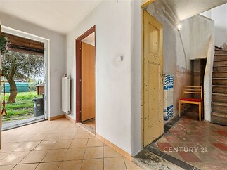 Vstupní chodba s dlažbou, nabízí přístup na zahradu, dřevěné schodiště vede do horního patra, prosvětlený prostor s možností úprav.