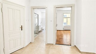 Chodba s dlažbou, vedoucí do koupelny a ložnice. Dřevěné parketové podlahy v ložnici, velká okna zajišťující světlost a moderní vzhled.